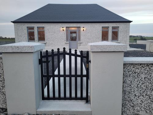 a white house with a gate in front of it at Maisie and Bea's cottage in Galway