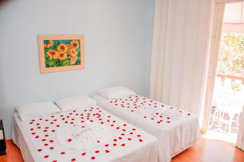 two beds with red hearts on them in a room at Pousada Arco-Íris in Lambari