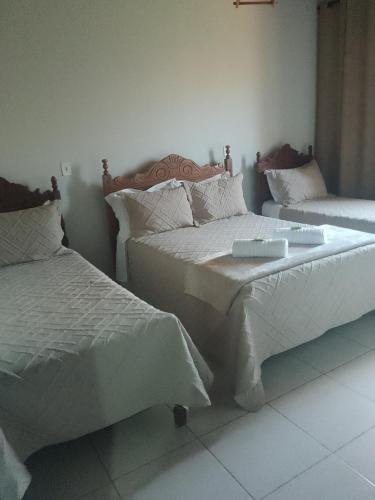 een slaapkamer met 2 bedden en witte lakens bij Pousada Vivenda Letícia in Prados