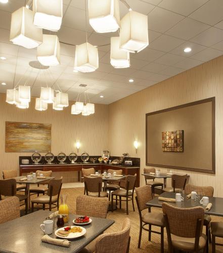 a dining room with tables and chairs and chandeliers at Holiday Inn St Louis SW - Route 66 by IHG in Saint Louis