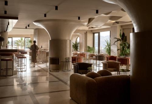 a person standing in a lobby with chairs and tables at Seaside A Lifestyle Resort - Adults Only in Agia Pelagia