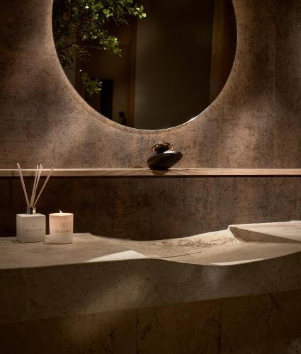 a bathroom with a mirror and a sink with two candles at Seaside A Lifestyle Resort - Adults Only in Agia Pelagia
