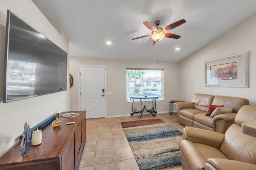 een woonkamer met een bank en een plafondventilator bij Summer all year round home in Phoenix