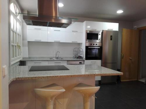 a kitchen with white cabinets and a counter with stools at Atico en el centro UAT00614 in Pamplona