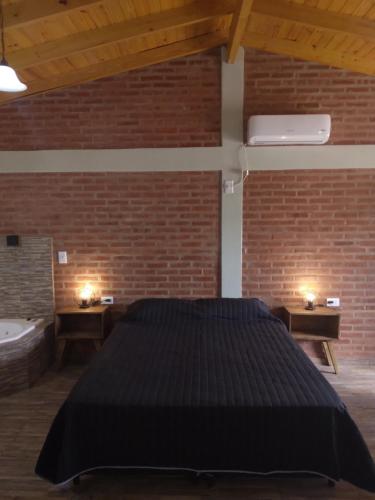 a bedroom with a large bed and a brick wall at Luz Alba Cabañas in Mina Clavero
