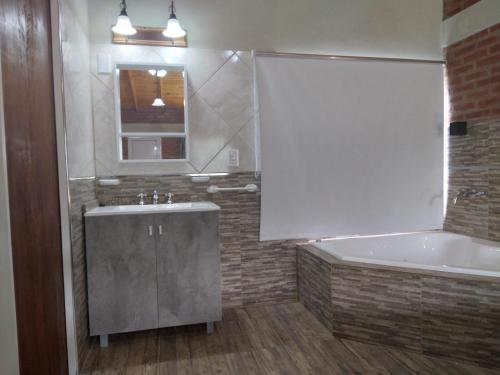 a bathroom with a sink and a tub and a window at Luz Alba Cabañas in Mina Clavero