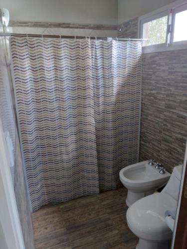 a bathroom with a shower curtain and a toilet at Luz Alba Cabañas in Mina Clavero