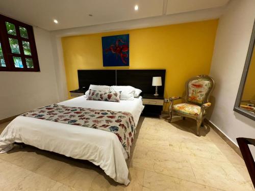 1 dormitorio con 1 cama grande y 1 silla en Porto Bello Hotel Boutique, en Puerto Colombia