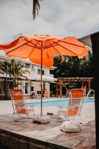 two chairs and an umbrella next to a pool at Pousada Recanto das Cerejeiras in Rio Grande