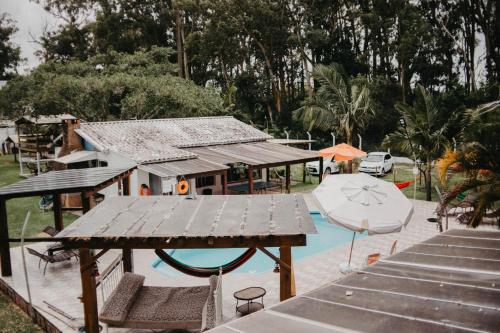 a pool with a house and a table and an umbrella at Pousada Recanto das Cerejeiras in Rio Grande
