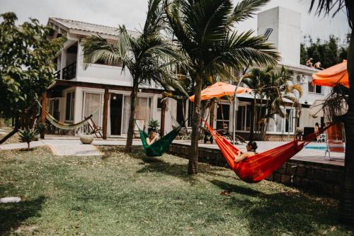 two people laying in hammocks in a yard next to a house at Pousada Recanto das Cerejeiras in Rio Grande