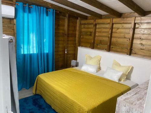 Schlafzimmer mit gelbem Bett und blauen Vorhängen in der Unterkunft LA ROSE DE CHAMP FLEURY in Labuthie