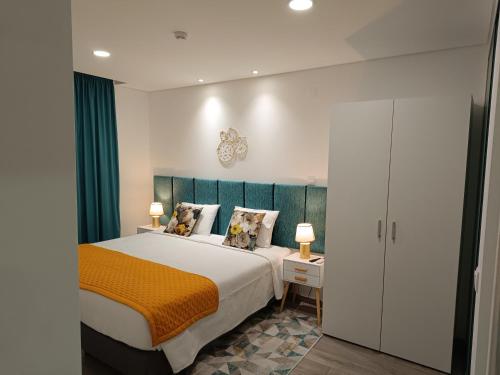 una camera da letto con un grande letto con una coperta arancione di Garden House Fundão - Apartamento 201 com 2 quartos com vista jardim a Fundão