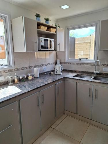 a kitchen with white cabinets and a sink and two windows at Cordillera sur in Esquel