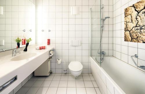 a bathroom with a tub and a toilet and a sink at Leonardo Boutique Hotel Berlin City South in Berlin