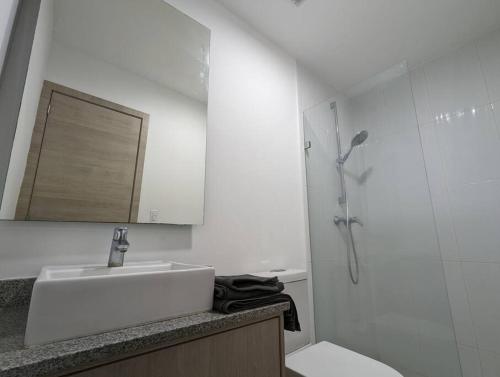 uma casa de banho branca com um lavatório e um chuveiro em Suite studio Ph - Metro la Carolina em Quito
