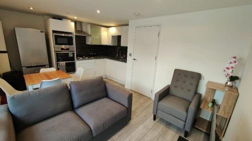 a living room with a couch and two chairs and a kitchen at flat 2 Wimbledon in London