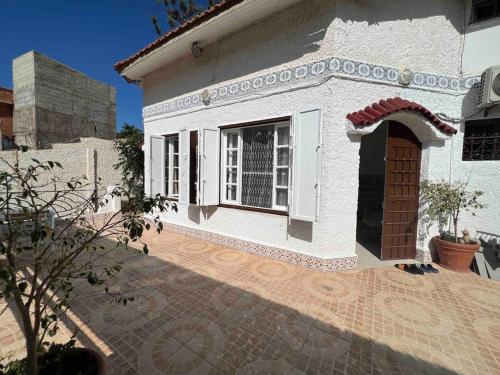 a small white house with a window and a patio at Magnifique Villa avec garage à 2min de la plage Saint-Rock, Ain El Turk, Oran in 'Aïn el Turk
