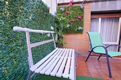 un banco blanco y una silla verde en un patio en Apart 2 terrazas para 4 personas Bilbao centro, en Bilbao