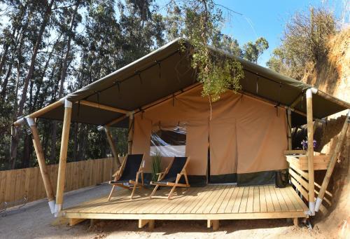 a tent with two chairs on a wooden deck at Parque Laguna de Zapallar in Maitencillo
