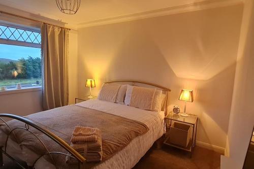 - une chambre avec un lit, deux lampes et une fenêtre dans l'établissement Hebridean Country House, à Lochs