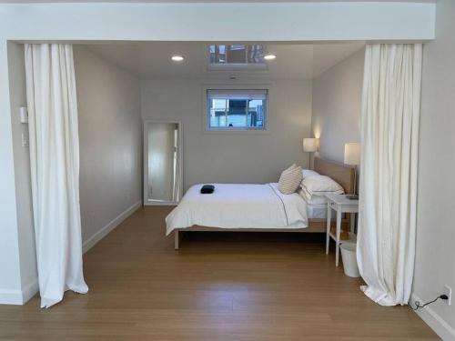 1 dormitorio con 1 cama con sábanas blancas y ventana en Le Citadin - Maison neuve moderne & ensoleillée, en Quebec
