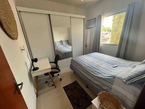 a small bedroom with a bed and a desk and a window at Sonho de Itaúna in Saquarema