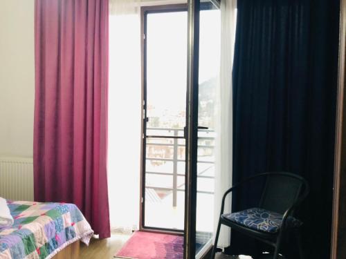 a bedroom with a bed and a chair and a window at Borjomi inn in Borjomi