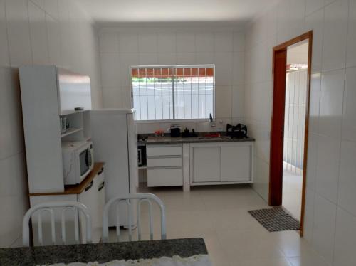 a kitchen with a white refrigerator and a microwave at Casa da Praia: o mar a apenas 500 metros de você in Itanhaém