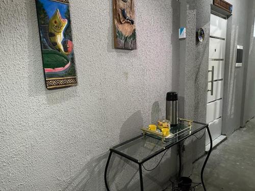 a glass table against a wall with paintings on the wall at Pousada da Onça - Itapiranga, AM in Itapiranga