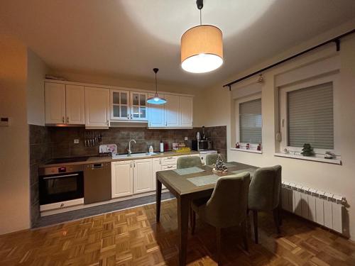 a kitchen with a table and chairs and a kitchen with white cabinets at Apartman Obala in Bosanska Gradiška