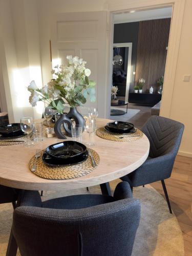 a dining room table with chairs and a vase of flowers at Belm Ferienwohnung am Bach in Belm
