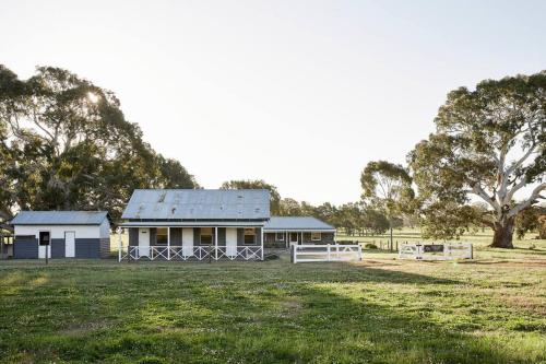 a small white house in a field with trees at Stoneycroft Cottage ~ Grampians Farm Stay 