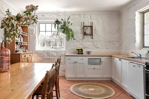 a kitchen with white cabinets and a wooden table at Stoneycroft Cottage ~ Grampians Farm Stay 