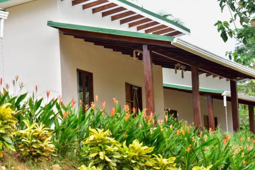 a house with a lot of flowers in front of it at Tarcoles Birding Lodge in Tarcoles