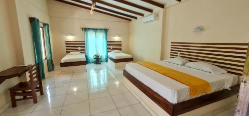 a bedroom with two beds and a desk in it at Tarcoles Birding Lodge in Tarcoles