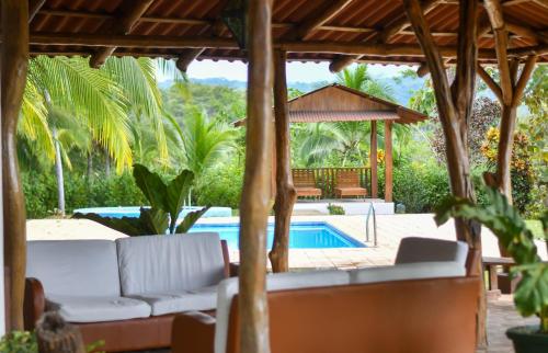 a patio with a couch and a gazebo and a pool at Tarcoles Birding Lodge in Tárcoles