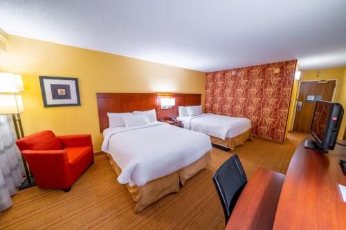 a hotel room with two beds and a chair at Sonesta Select in Bettendorf