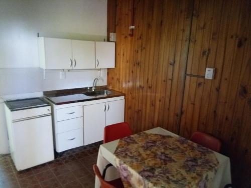 a kitchen with white cabinets and a table with chairs at Lavalle hostel in Posadas