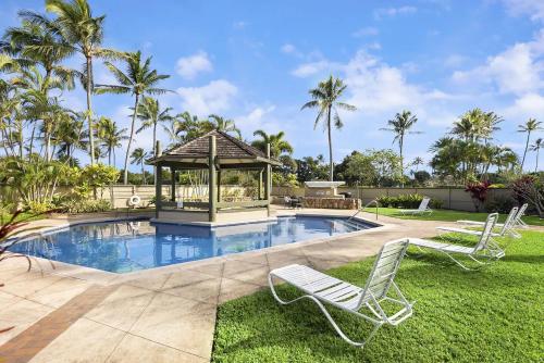 a gazebo and two lawn chairs next to a swimming pool at Hale Nalu Townhouse at Turtle Bay Golf Course in Kahuku