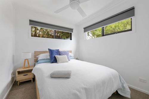 a white bedroom with a bed and two windows at Halcyon Days in San Remo