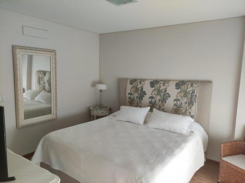 a bedroom with a white bed and a mirror at Excelente Vista al Golf y al Mar in Mar del Plata