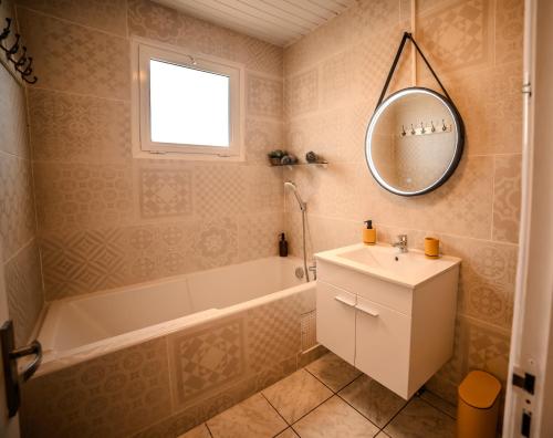 a bathroom with a sink and a tub and a mirror at Lilie location sud in Petite Île
