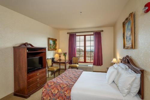 Schlafzimmer mit einem Bett, einem TV und einem Schreibtisch in der Unterkunft Silverland Inn in Virginia City