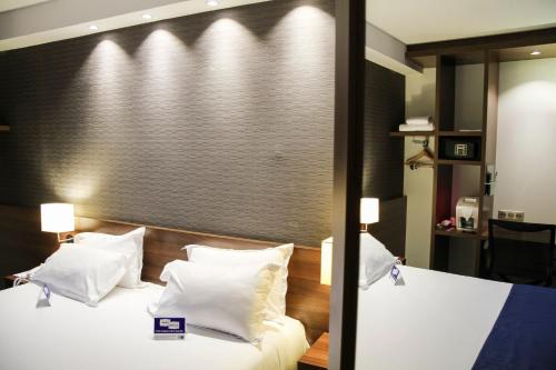 a hotel room with a bed with white pillows at Holiday Inn Express Amiens by IHG in Amiens