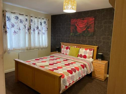 a bedroom with a bed with a red and white comforter at Falconwood Apartment in Manchester