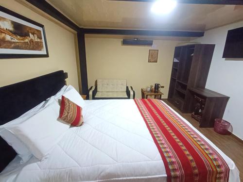 1 dormitorio con 1 cama blanca grande y 1 silla en La Posada del Viajero en Cuzco