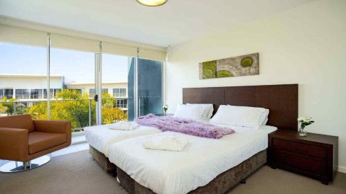 a bedroom with a large bed and a chair at 2BR Resort Living: 2-Bed Haven in Gold Coast