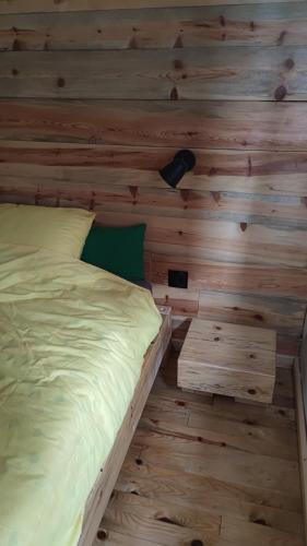 una cama en una habitación con una pared de madera en TANA, en Rača