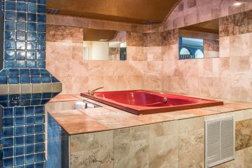 a red bath tub in a bathroom with blue tiles at Country Inn & Suites by Radisson, Battle Creek, MI in Battle Creek
